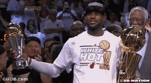 Man In White Hot Shirt Holding Two Trophies GIF