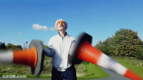 Man In White Jacket Holding Two Traffic Cones GIF
