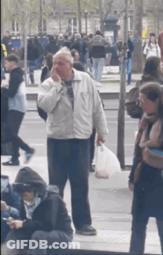 Man In White Jacket On Phone In Crowded Street GIF