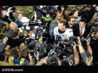 Man In White Jersey Surrounded By Crowd Taking Pictures GIF