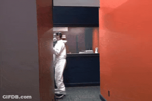 Man In White Jumpsuit In Hallway GIF