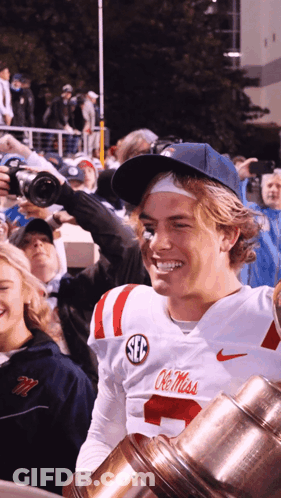 Man In White Ole Miss Jersey Holding Trophy GIF