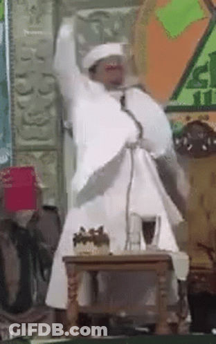 Man In White Robe Speaking At Microphone GIF