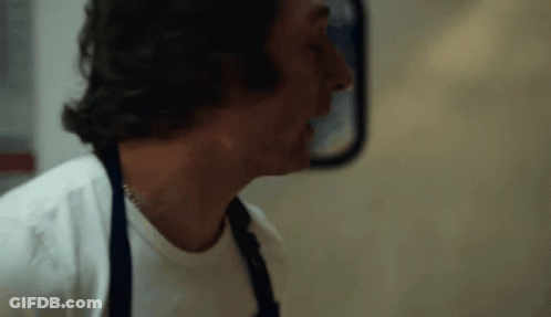 Man In White Shirt And Apron In Front Of Mirror GIF