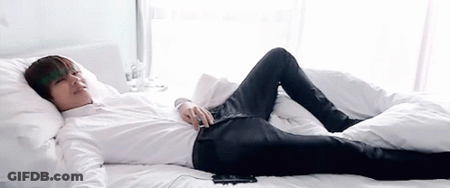 Man In White Shirt And Black Jeans Lying On Bed GIF