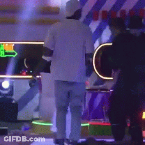 Man In White Shirt And Blue Jeans On Stage With People GIF
