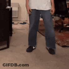 Man In White Shirt And Blue Jeans Standing On Carpet GIF