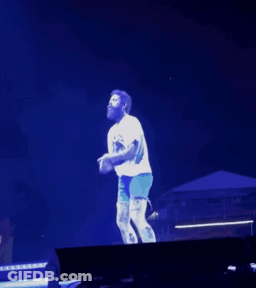 Man In White Shirt And Blue Shorts Dancing On Stage In Front Of Crowd GIF