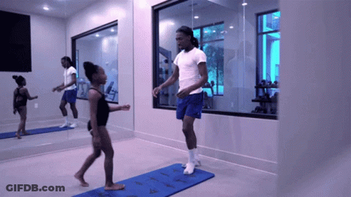 Man In White Shirt And Blue Shorts Jumping Over Blue Mat In Gym GIF