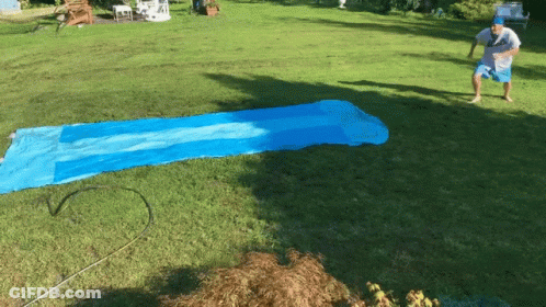 Man In White Shirt And Blue Shorts On Water Slide GIF