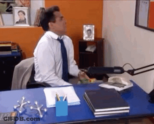 Man In White Shirt And Blue Tie At Desk With Calculator GIF