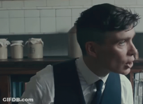 Man In White Shirt And Blue Vest Looking To Side GIF