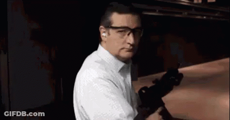 Man In White Shirt And Glasses Holding Gun GIF