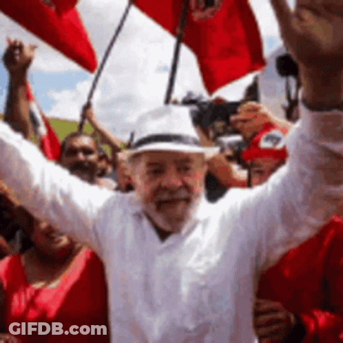 Man In White Shirt And Hat Holding Red Flags GIF