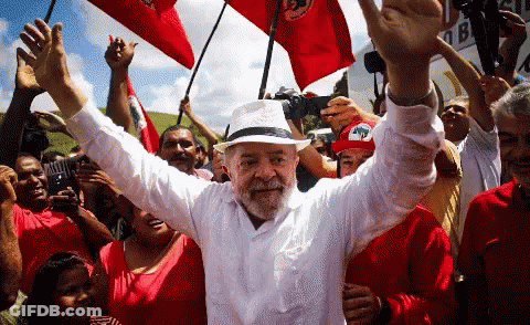 Man In White Shirt And Hat Surrounded By People GIF