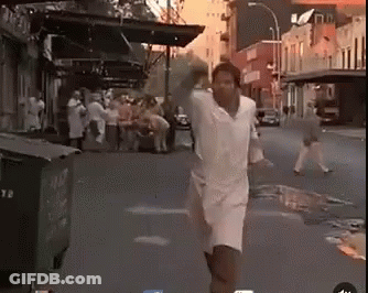 Man In White Shirt And Shorts Running Down Street GIF