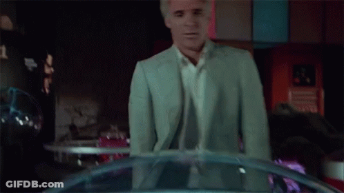 Man In White Shirt And Suit Looking In Dark Room GIF