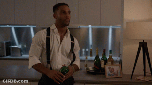 Man In White Shirt And Suspenders Holding Bottle GIF