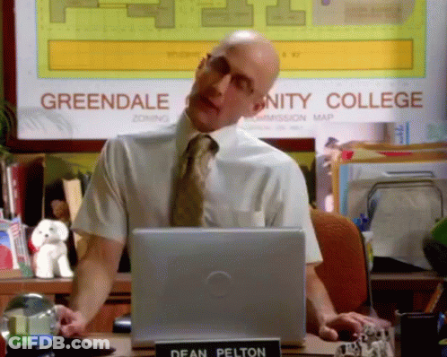 Man In White Shirt And Tie At Greendale Community College Sign GIF