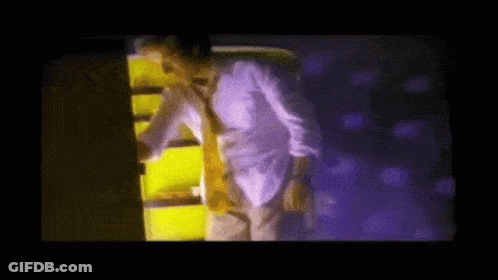 Man In White Shirt And Tie In Front Of Purple Wall GIF