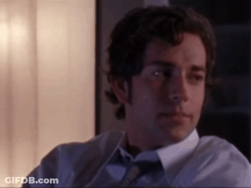 Man In White Shirt And Tie Sitting In Dark Room GIF