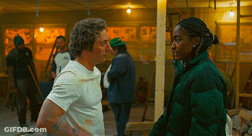 Man In White Shirt And Woman In Green Jacket Talking GIF
