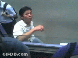 Man In White Shirt At Table In Crowd GIF