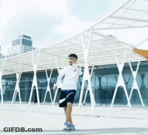 Man In White Shirt Blue Shorts Under Umbrella GIF