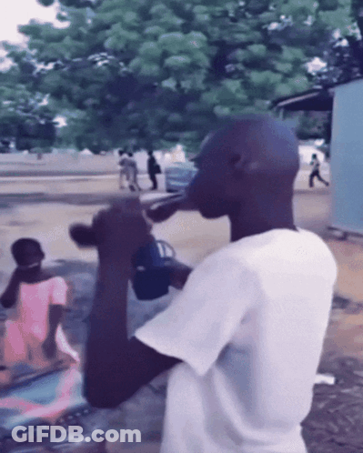 Man In White Shirt Drinking From Bottle Outside GIF