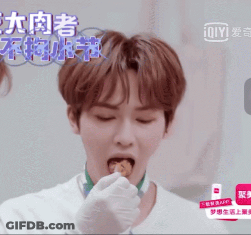 Man In White Shirt Eating Food In Front Of Ioiyi Ad GIF