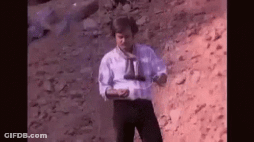 Man In White Shirt Holding Binoculars On Rocky Hill GIF
