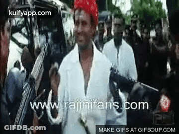 Man In White Shirt Holding Gun In Front Of Crowd GIF
