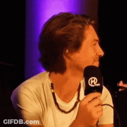 Man In White Shirt Holding Microphone With Letter R GIF