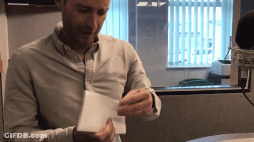 Man In White Shirt Holding Paper At Window GIF