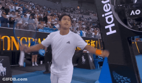 Man In White Shirt Holding Tennis Racquet In Front Of Haier Banner GIF
