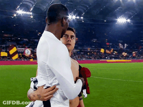 Man In White Shirt Hugging Man In Red Shirt On Soccer Field GIF