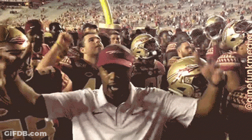 Man In White Shirt In Front Of Football Helmets GIF