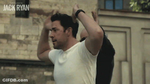 Man In White Shirt In Front Of Jack Ryan Wall GIF