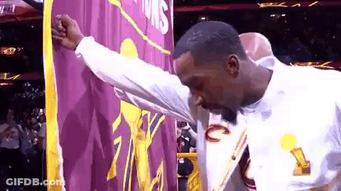 Man In White Shirt In Front Of Purple And Yellow Banner GIF