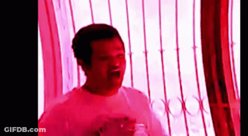Man In White Shirt In Front Of Window With Red Light GIF