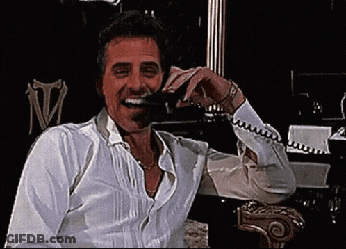 Man In White Shirt Laughing And Talking On Phone GIF