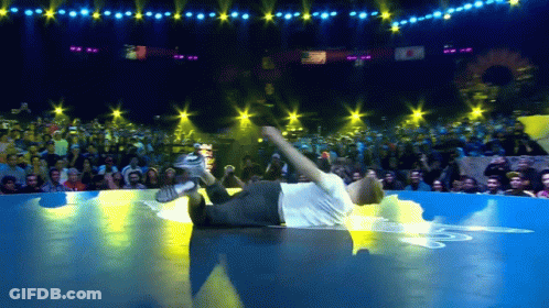 Man In White Shirt Laying On Floor In Front Of Crowd GIF
