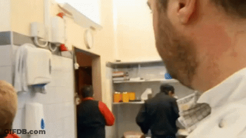 Man In White Shirt Looking At People In Kitchen GIF
