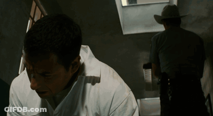 Man In White Shirt Looking Down With Cowboy Behind GIF