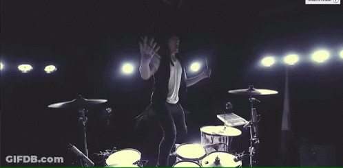 Man In White Shirt Playing Drum Set On Stage GIF