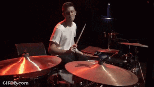 Man In White Shirt Playing Drums In Dark Room GIF