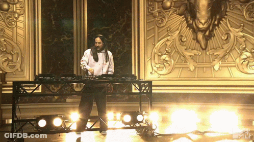Man In White Shirt Playing Music In Front Of Gold Wall GIF