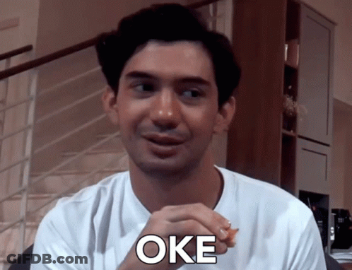 Man In White Shirt Saying Oke In Front Of Stairs GIF