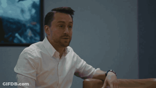 Man In White Shirt Sits On Couch In Front Of Picture GIF