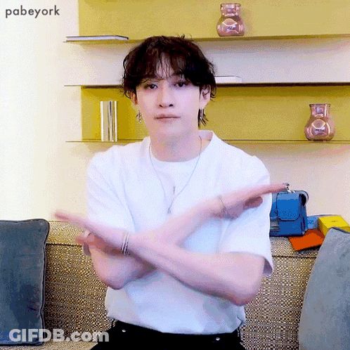 Man In White Shirt Sitting Arms Crossed In Front Of Pabeyork Wall GIF